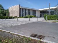 a big white building next to a street and some trees and grass on both sides of the road