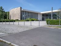 a big white building next to a street and some trees and grass on both sides of the road