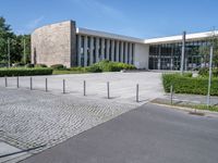 a big white building next to a street and some trees and grass on both sides of the road