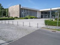 a big white building next to a street and some trees and grass on both sides of the road