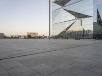 a large building reflecting a glass wall is in the distance with another building and tower on either side of it