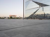 a large building reflecting a glass wall is in the distance with another building and tower on either side of it