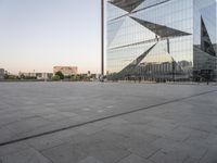 a large building reflecting a glass wall is in the distance with another building and tower on either side of it