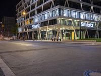 a picture of the building by the road at night with the reflection on the glass windows