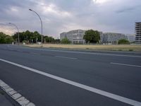 empty road with traffic signs near large building and parking lot in background at dusk time