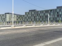 an empty road in front of buildings and a car driving across it and the lady is walking on the bridge