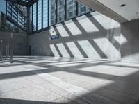 the sun casts a long shadow through some glass walls in an empty building lobby on a sunny day