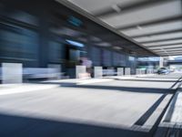 blurred image of an airport with a train passing by and people standing at the curb waiting area