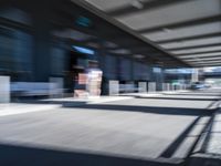 blurred image of an airport with a train passing by and people standing at the curb waiting area