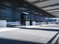 blurred image of an airport with a train passing by and people standing at the curb waiting area