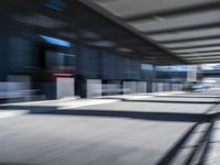 blurred image of an airport with a train passing by and people standing at the curb waiting area