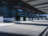 blurred image of an airport with a train passing by and people standing at the curb waiting area