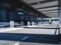 blurred image of an airport with a train passing by and people standing at the curb waiting area