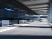 blurred image of an airport with a train passing by and people standing at the curb waiting area