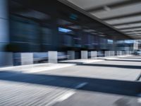 blurred image of an airport with a train passing by and people standing at the curb waiting area