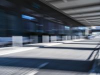 blurred image of an airport with a train passing by and people standing at the curb waiting area