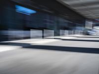 blurred image of an airport with a train passing by and people standing at the curb waiting area