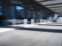 blurred image of an airport with a train passing by and people standing at the curb waiting area