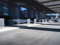 blurred image of an airport with a train passing by and people standing at the curb waiting area