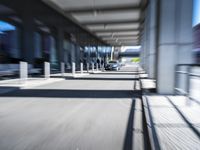 blurred image of an airport with a train passing by and people standing at the curb waiting area