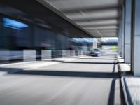 blurred image of an airport with a train passing by and people standing at the curb waiting area