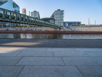 a skateboarder riding on a cement ramp next to a city street under a bridge