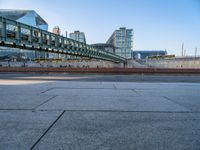 a skateboarder riding on a cement ramp next to a city street under a bridge