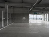 a parking garage with a closed door to the side of it, and a no parking sign at the end of the aisle