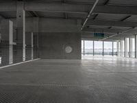 a parking garage with a closed door to the side of it, and a no parking sign at the end of the aisle