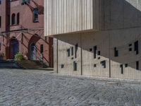 cobblestone driveway surrounded by modern buildings on sunny day with sun reflecting onto the windows