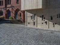 cobblestone driveway surrounded by modern buildings on sunny day with sun reflecting onto the windows