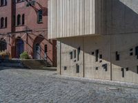 cobblestone driveway surrounded by modern buildings on sunny day with sun reflecting onto the windows