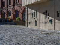 cobblestone driveway surrounded by modern buildings on sunny day with sun reflecting onto the windows