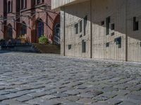 cobblestone driveway surrounded by modern buildings on sunny day with sun reflecting onto the windows