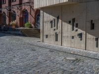 cobblestone driveway surrounded by modern buildings on sunny day with sun reflecting onto the windows