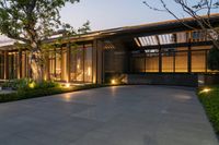 a contemporary home that features black concrete and glass walls, including windows, a covered patio and a wood deck