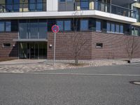 a sign that has the number two on it by a road by a building with large windows