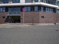 a sign that has the number two on it by a road by a building with large windows