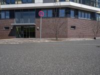 a sign that has the number two on it by a road by a building with large windows