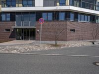 a sign that has the number two on it by a road by a building with large windows