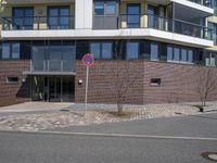 a sign that has the number two on it by a road by a building with large windows