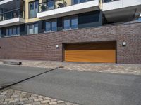 a brick building with two yellow garage doors on the side of it and a stone sidewalk