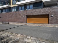 a brick building with two yellow garage doors on the side of it and a stone sidewalk