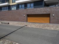 a brick building with two yellow garage doors on the side of it and a stone sidewalk