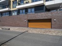 a brick building with two yellow garage doors on the side of it and a stone sidewalk