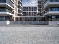 three tall building near the concrete fence and a parking lot with a bench near one of the buildings