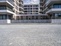 three tall building near the concrete fence and a parking lot with a bench near one of the buildings