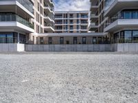 three tall building near the concrete fence and a parking lot with a bench near one of the buildings