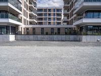 three tall building near the concrete fence and a parking lot with a bench near one of the buildings