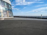 the empty parking lot has a wall of windows on it with water and buildings in the background